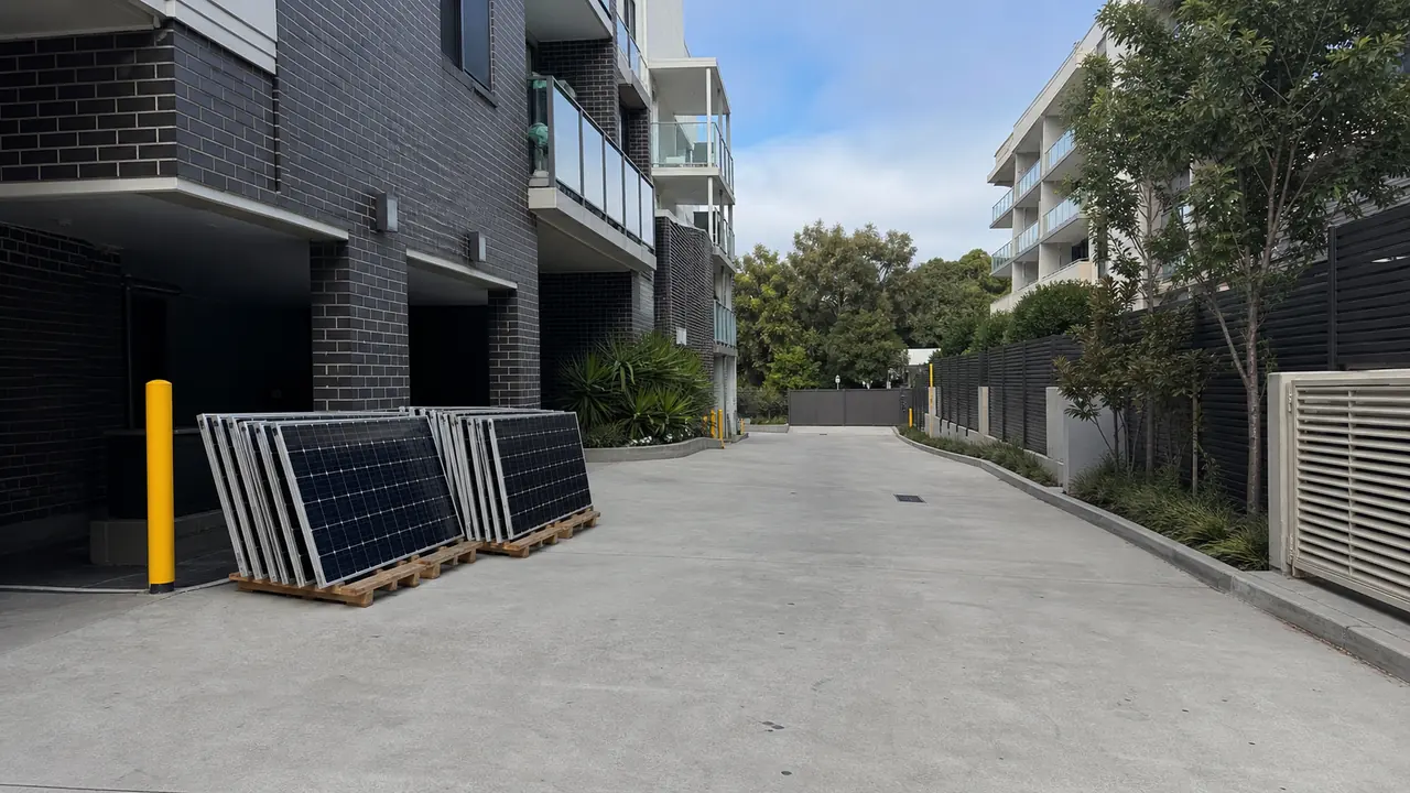 Safely staged removed solar panels beside a clear shared driveway at an apartment building